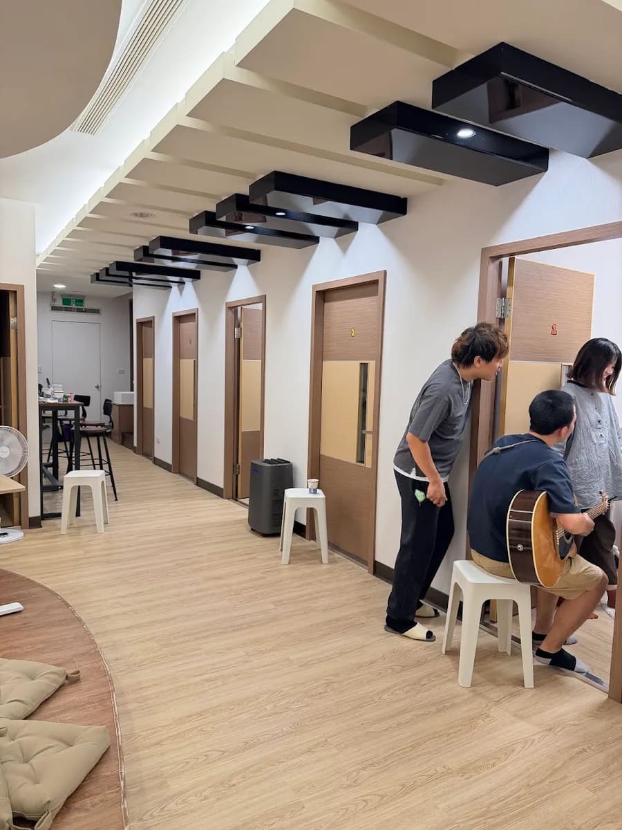 學生在走廊練習木吉他，老師在旁陪伴的上課日常