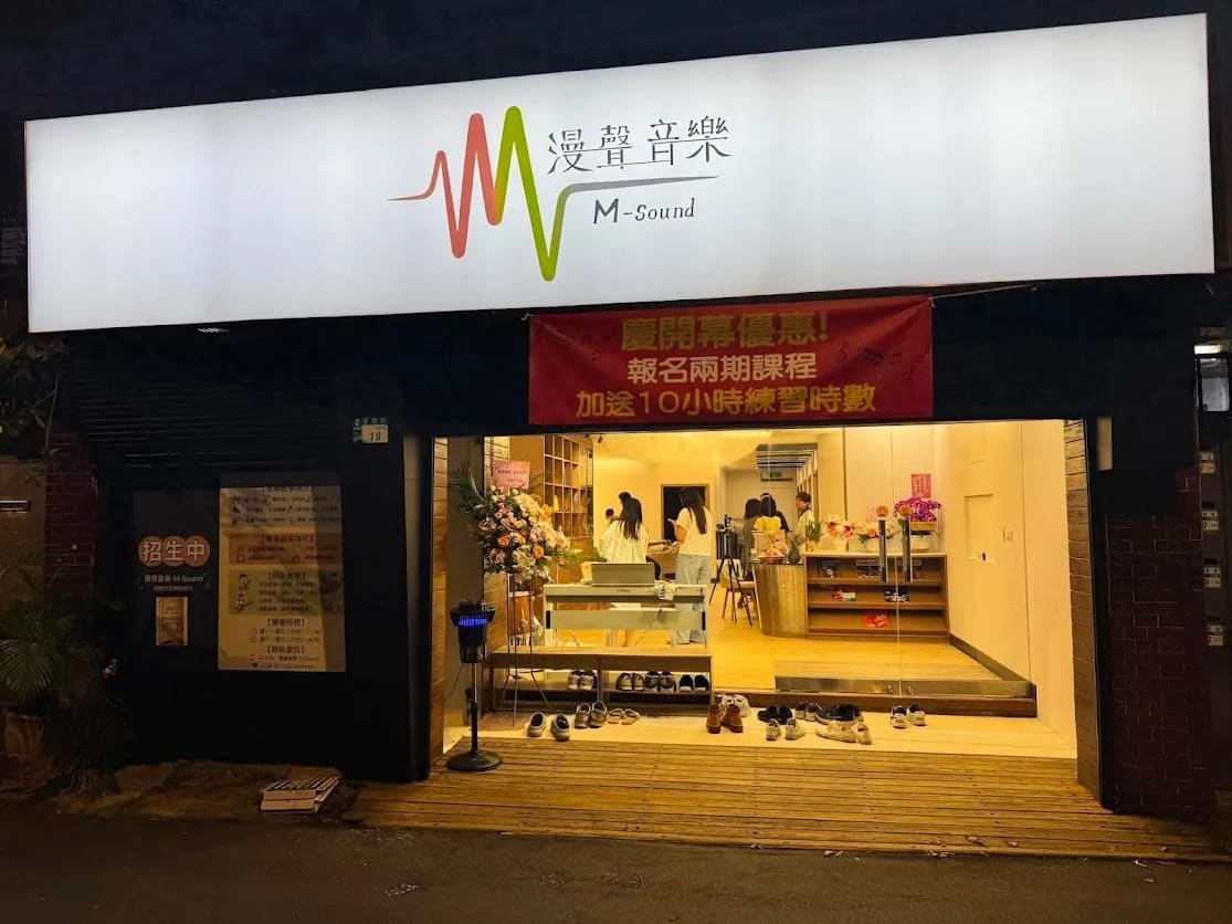漫聲音樂夜間店面，招牌燈亮起，室內溫暖燈光與開幕花籃