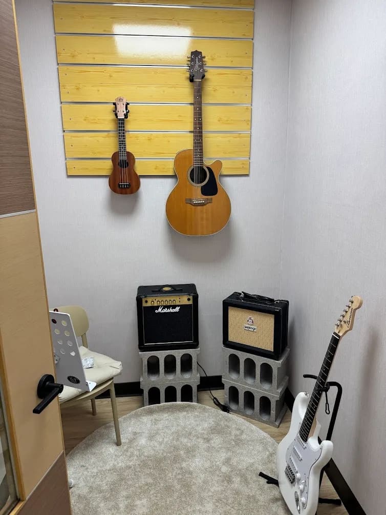 吉他教室，黃色木紋掛牆展示烏克麗麗與木吉他，Marshall 音箱